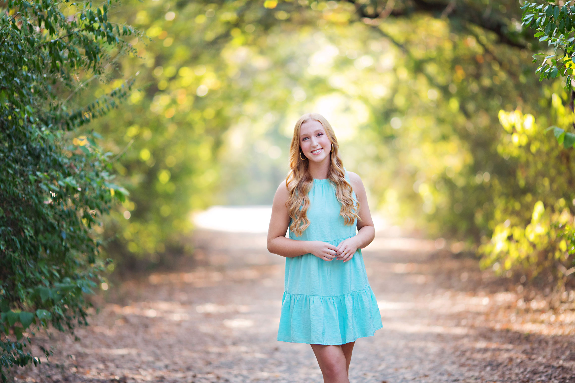Girl posing wearing blue dress out in nature for senior portraits